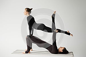 Women practicing acroyoga on yoga mat