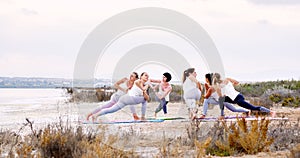 Women practising yoga do Side Angle Pose or Parivrtta Parsvakonasana outdoors