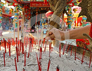 Women pray to Chinese gods by incense sticks at the shrine