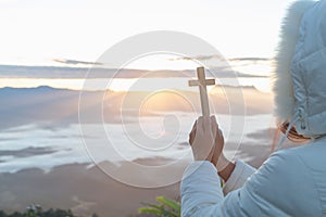 Women pray to god with the cross on the mountain background with morning sunrise. Woman Pray for god blessing to wishing have a