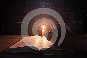 Women praying on the Bible in the light candles selective focus