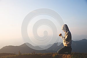 A women is praying to God on the mountain. Praying hands with faith in religion and belief in God on blessing background. Power of