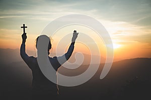 A women is praying to God on the mountain. Praying hands with faith in religion and belief in God on blessing background. Power of