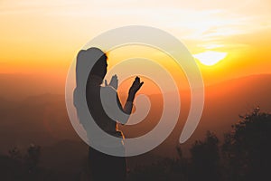 A women is praying to God on the mountain. Praying hands with faith in religion and belief in God on blessing background. Power of