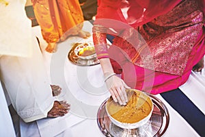 Women preparaing for pasting the turmeric haldi oil mixed with milk on bride`s feet and body