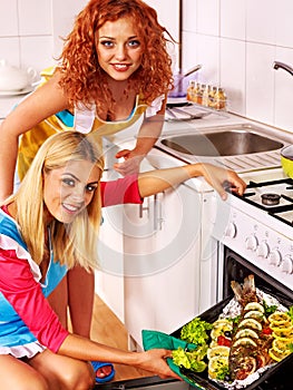 Women prepare fish in oven.