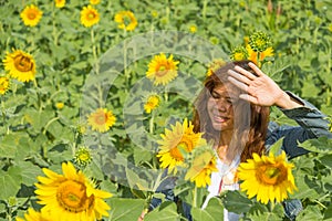Women is protect her face from sun light in sunflowers field
