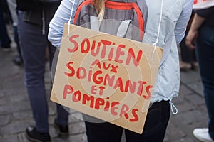 women protesting in the street with text on cardboard in french : soutien aux signets et pompiers, in English : support