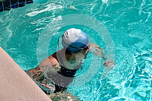 Women pushing off the wall of a pool while swimming laps