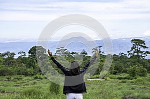 Women raise their arms looked at the mountains and trees at Phu Hin Rong Kla National Park , Phetchabun in Thailand
