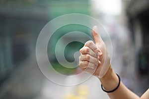 Women raise up the thumb with blur green background near sky train, Bangkok, Thailand