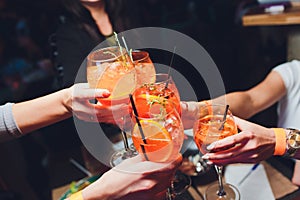 Women raising a glasses of aperol spritz at the dinner table.