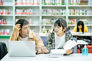 Women read books and men use laptops to search for books in libraries