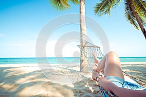 Women relax and sunbathe on hammock at sandy tropical beach