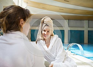 Women relaxing by the poolside wearing toweling robes