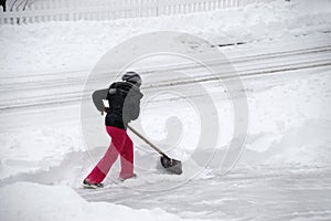 Women removing snow on the driveway by shovel after blizzard