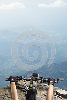 Women riding on a bicycle handlebar top of a mountain view