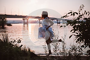 Women running at sunset. Lifestyle full-length portrait of a beautiful young woman in a long white dress running along