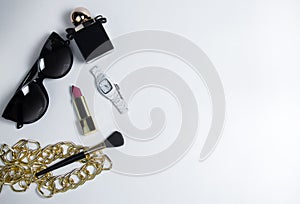 Women's accessories in black and cosmetics on a white background. Top view of the desktop for women