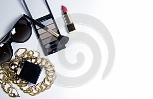 Women's accessories in black and cosmetics on a white background. Top view of the desktop for women