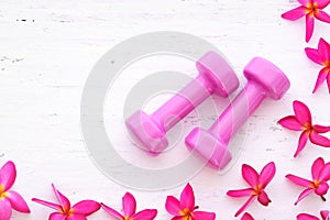 Women`s active fitness lifestyle concept. Pink dumbbells with pi