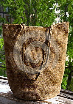 Women\'s bag made of raffia on a background of green trees