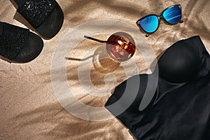 Women`s beach accessories or summer outfit on sand background. Top view with copy space