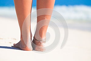 Women's beautiful smooth legs on white sand beach