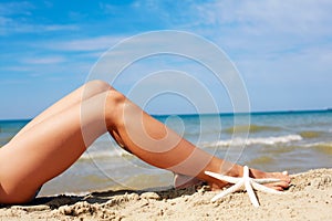 Women`s beautiful tan legs on the beach