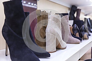 Women's boots with heels on the shelves in the store. Fashion, style and beauty. Close-up