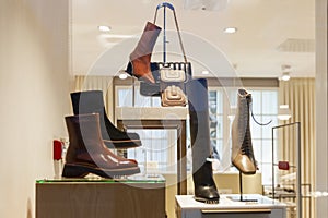 Women`s boots, shoes and bags in a shop window. Fashion and style of the new autumn-winter season