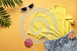 Women`s casual outfit of a traveler, summer party. denim shorts, colorful T-shirt and sun glasses
