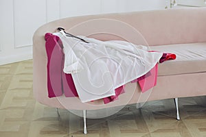 Women's clothes lie on a pink sofa in front of a choice