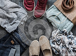 Women`s clothing on a dark background, top view. Shopping concept. Autumn women`s clothing - jeans, suede shoes, sneakers,