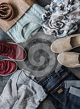 Women`s clothing on a dark background, top view. Shopping concept. Autumn women`s clothing - jeans, suede shoes, sneakers,