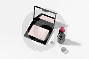 Women's compact powder with mirror and red lipstick with shadow on white isolated background.