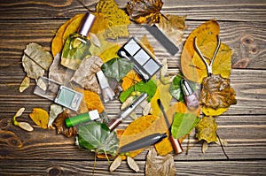 Women& x27;s cosmetics for make-up, objects for care of nails and perfumes lie on a wooden table in yellow autumn leaves.