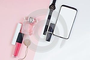 Women`s cosmetics on a pink white background. Lipstick, necklace, wrist watch, phone and perfume, beauty and fashion concept. Top