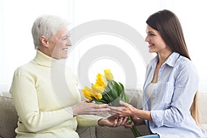 Women`s day. Daughter giving bouquet of tulips to mother