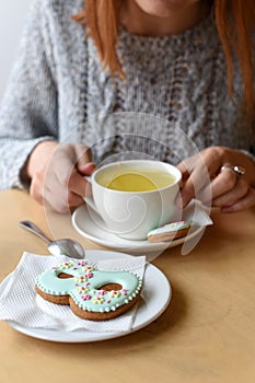 A Women`s day photo of woman`s hands, a tea pot, a cup and a cookie shaped like a figure `8`