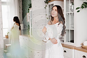 Women& x27;s day. Romantic attractive young woman 20-25 years with long curly hair in white dress is poses with crossed