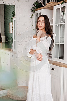 Women& x27;s day. Romantic  young woman 20-25 years with long curly hair in white dress is poses with crossed