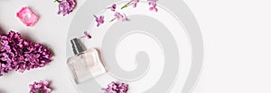Women`s day. Valentines day. Bottles of perfume and beautiful lilac flowers on white table. Banner
