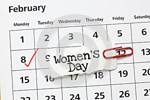 Women`s Day words written on a piece of paper placed on a calendar. March 8 Women`s Day