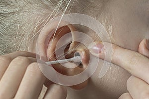 Women`s ear close-up to clean the cotton bud. deafness concept