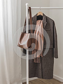 Women's English-style coat, cashmere scarf, leather bag on a floor hanger