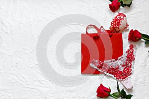 Women`s erotic underwear and red roses on white surface. Red lacy lingerie on white background. Concept of love. Flat