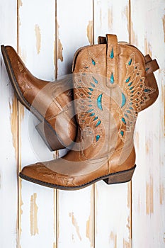 Women`s fashion boots with a pattern. Ladies vintage leather cowboy shoes. On white floor boards