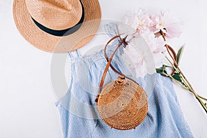 Women`s fashion summer clothes, accessories. Stylish female straw hat, blue dress, rattan bag, peony