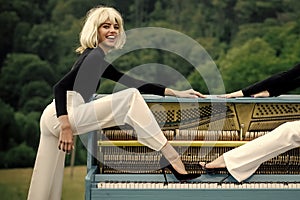 Women`s fashion. Women playing the grand piano with legs in fashionable shoes outdoor.